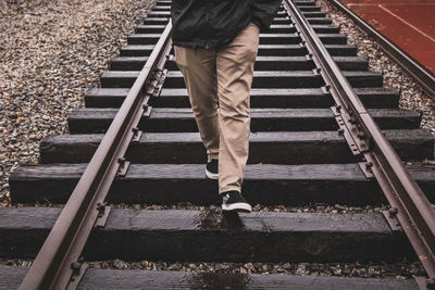 Low section of man walking on railroad track