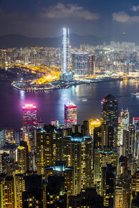 Illuminated modern buildings in city against sky at night