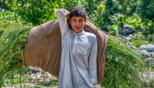 Portrait of young man holding plants in forest