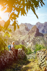 Girl resting on the hiking trail through arid rocky terrain. coculli village, santo antao cape verde