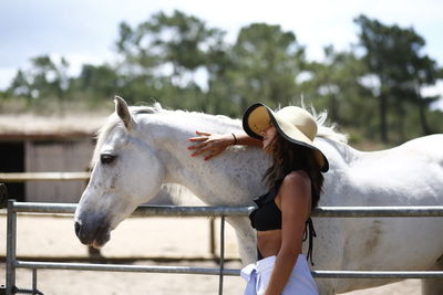 Side view of young woman standing by horse