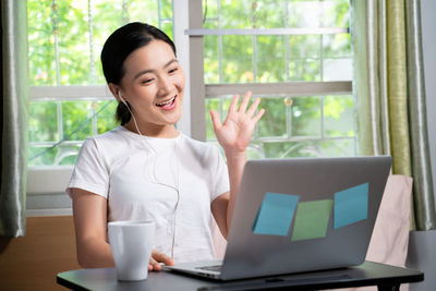 Young woman using mobile phone while sitting on table
