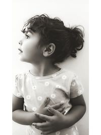 Girl looking away while standing against white background