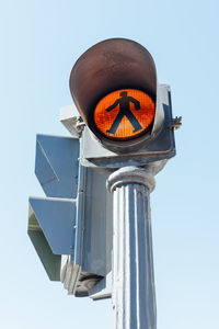Traffic light in orange amber with madrid blue sky background. spain.
