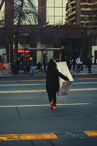 Rear view of people walking on road in city