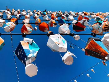 Low angle view of multi colored umbrellas against blue sky