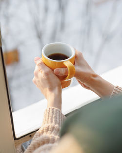 Cropped hand of woman holding coffee at home