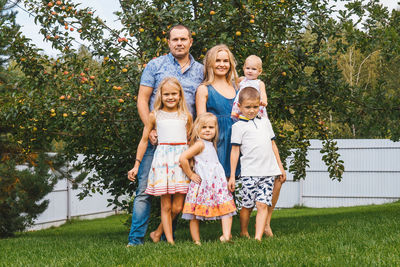 Portrait of family standing on grass against trees