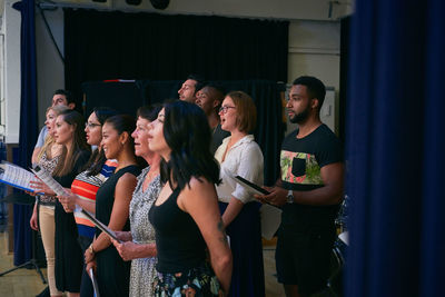 Multi-ethnic group of students singing in choir at school auditorium