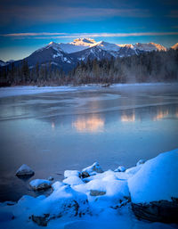 Scenic view of frozen lake by snowcapped mountains against sky