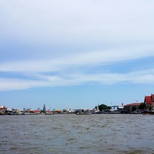 Sea by buildings in city against sky