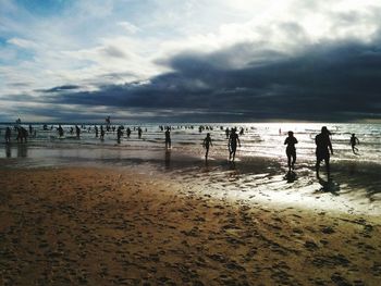 Silhouette people on beach against sky