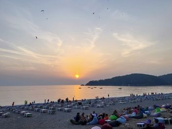 People on beach against sky during sunset