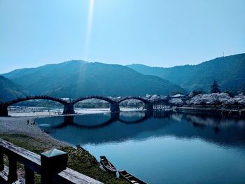 Arch bridge over river against clear blue sky