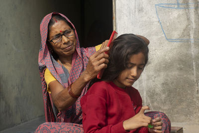 Woman combing daughter hair at home