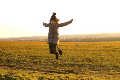 Man with dog on field against sky during sunset