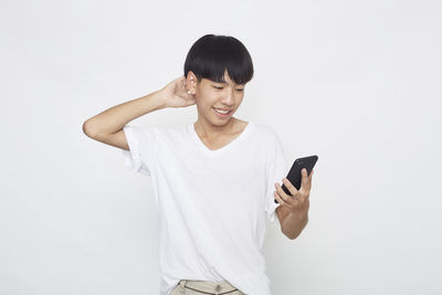 Young man using smart phone against white background