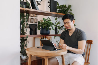 Young woman using laptop while sitting on chair at home