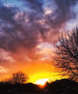 Low angle view of silhouette trees against dramatic sky