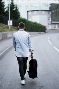 Rear view of man walking on road