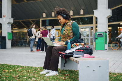 Young female student e-learning through laptop in campus