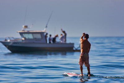 Full length of shirtless man standing in sea against sky