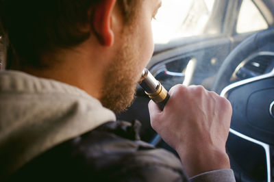 Man smoking electronic cigarette in car