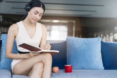 Young woman sitting on sofa at home