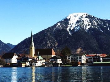 Buildings by mountains against clear sky