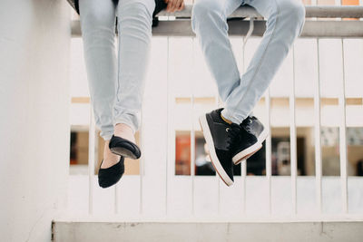 Low section of couple sitting on railing