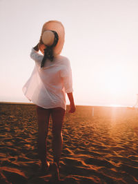 Man standing on beach against sky during sunset