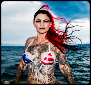 Portrait of young woman in sea against sky