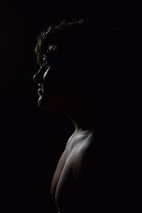 Close-up portrait of young woman against black background