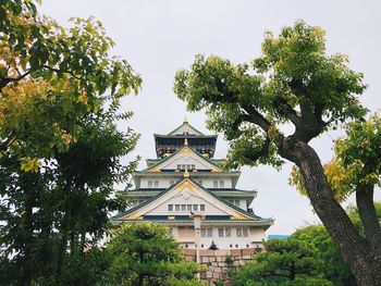 Low angle view of trees and building against sky