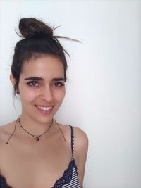 Portrait of a smiling young woman against wall