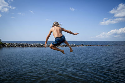 Boy jumping into sea