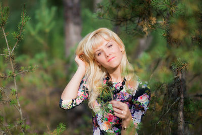 Portrait of young woman holding leaves in forest