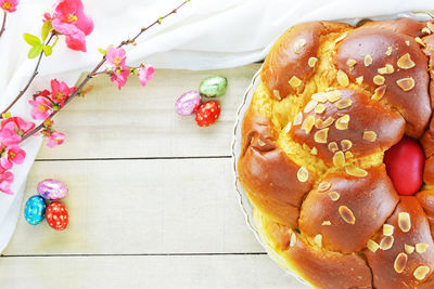 Easter bread ,mini chocolate eggs and  flowering quince on wooden table