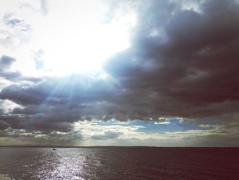 Sunlight streaming through clouds over sea