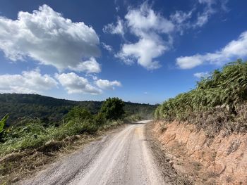 Road leading towards mountains against sky