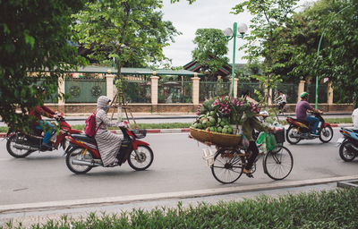 People riding motor scooters on road