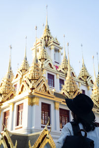 Rear view of man outside temple against building