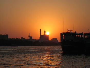 Silhouette of ship in sea during sunset