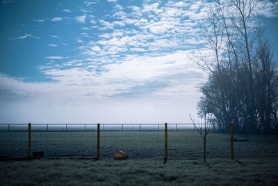 Wooden fence on field against sky