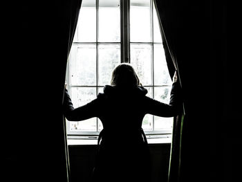 Rear view of woman standing against window