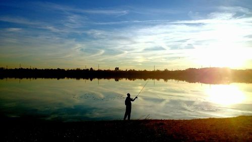 Silhouette of woman standing at lakeshore