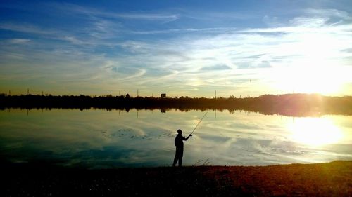 Silhouette of woman standing at lakeshore