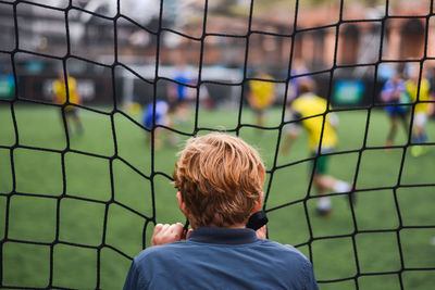 Rear view of boy standing on soccer field