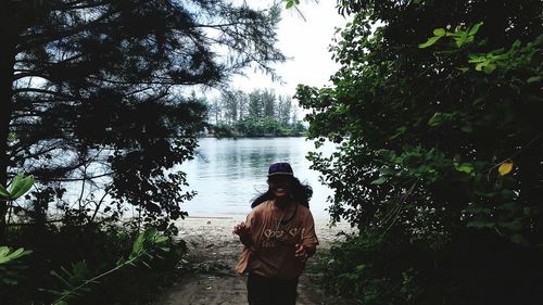 Rear view of woman standing by tree against sky