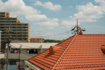 Low angle view of roof and buildings in town against sky